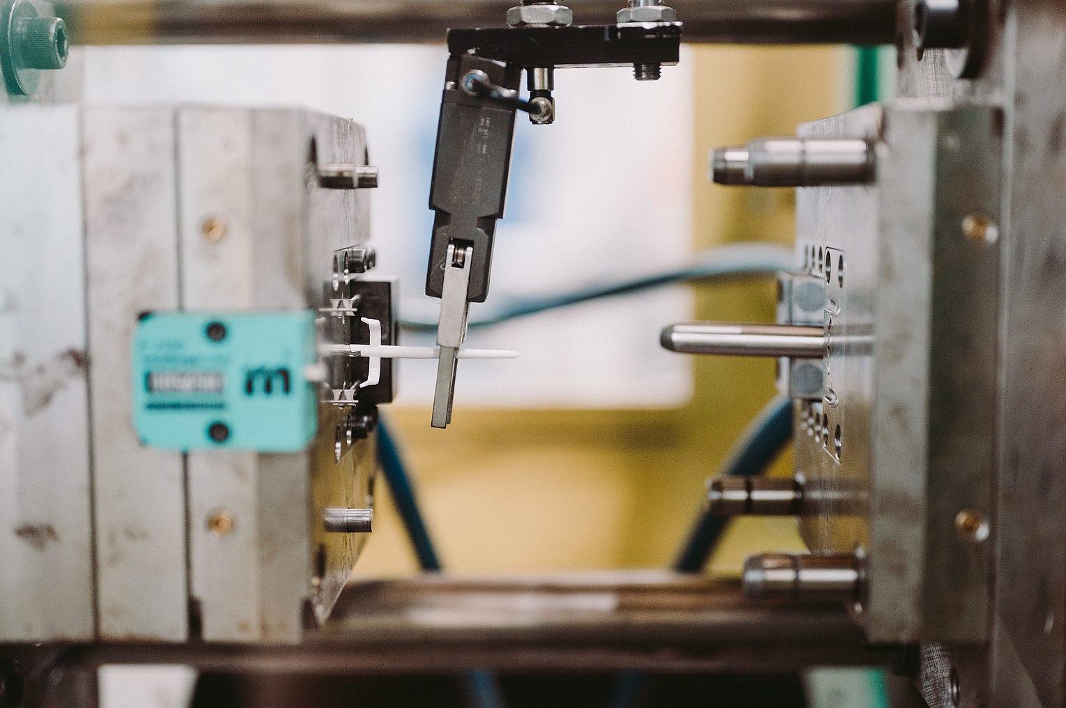 Roboter in der Produktion von Feinmechanikteilen greift nach Metallstift